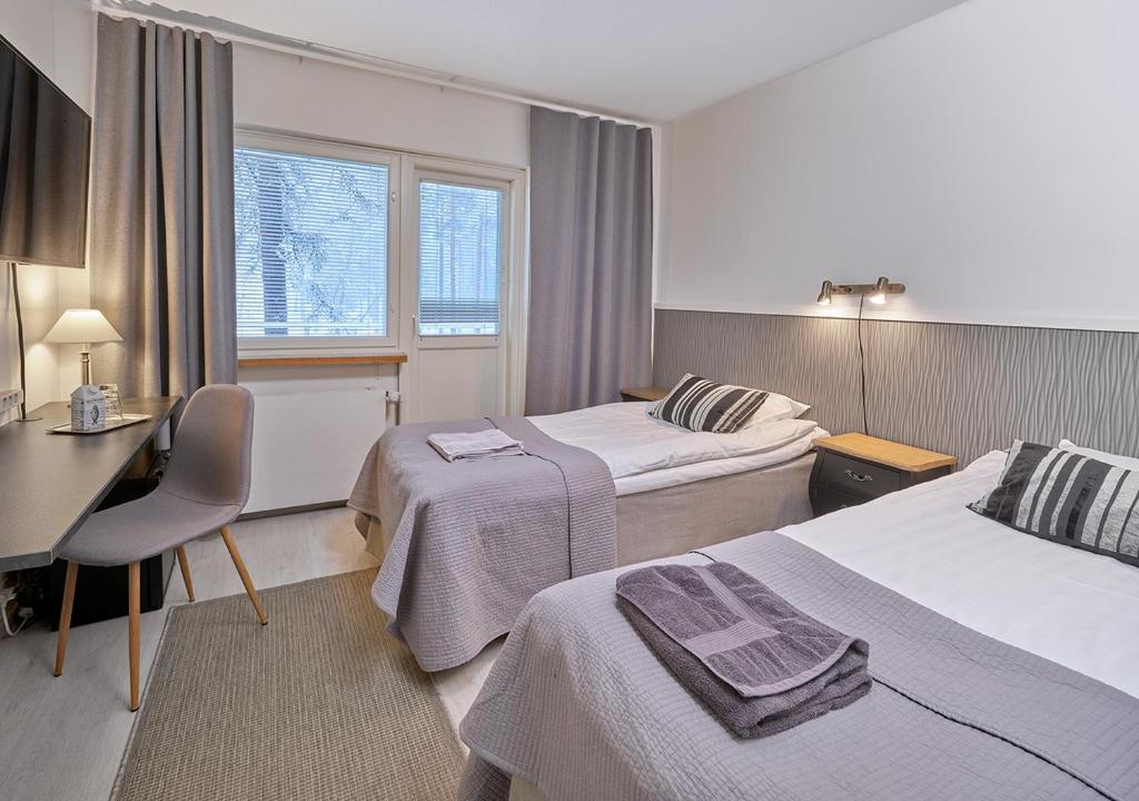 LohjaHotelli-Ravintola Gasthaus Lohja的酒店客房配有两张床和一张书桌