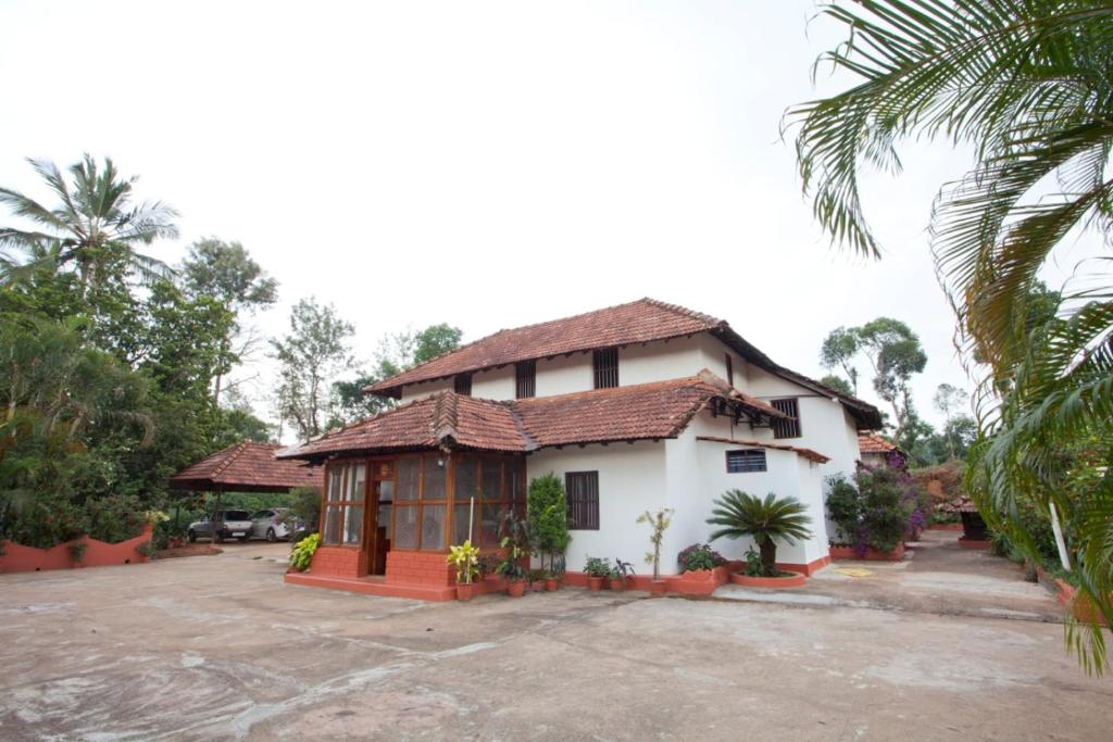 NapokluSardar Bahadur's Heritage Bungalow Estate Stay的前面有棕榈树的白色房子