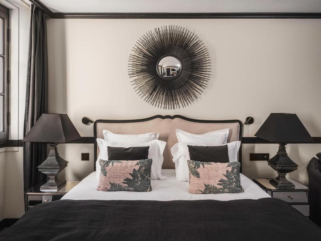 马赛Maisons du Monde Hôtel &amp; Suites - Marseille Vieux Port的一间卧室配有一张带两盏灯和镜子的床