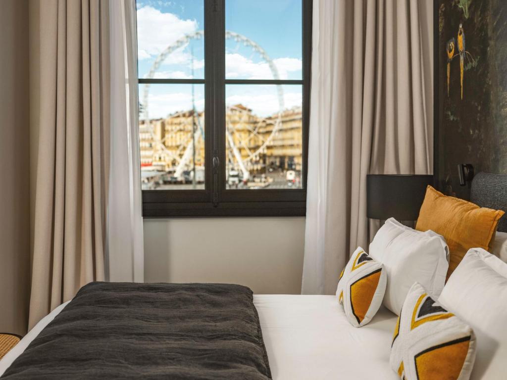 马赛Maisons du Monde Hôtel &amp; Suites - Marseille Vieux Port的一间卧室配有一张床,享有摩天轮的景色