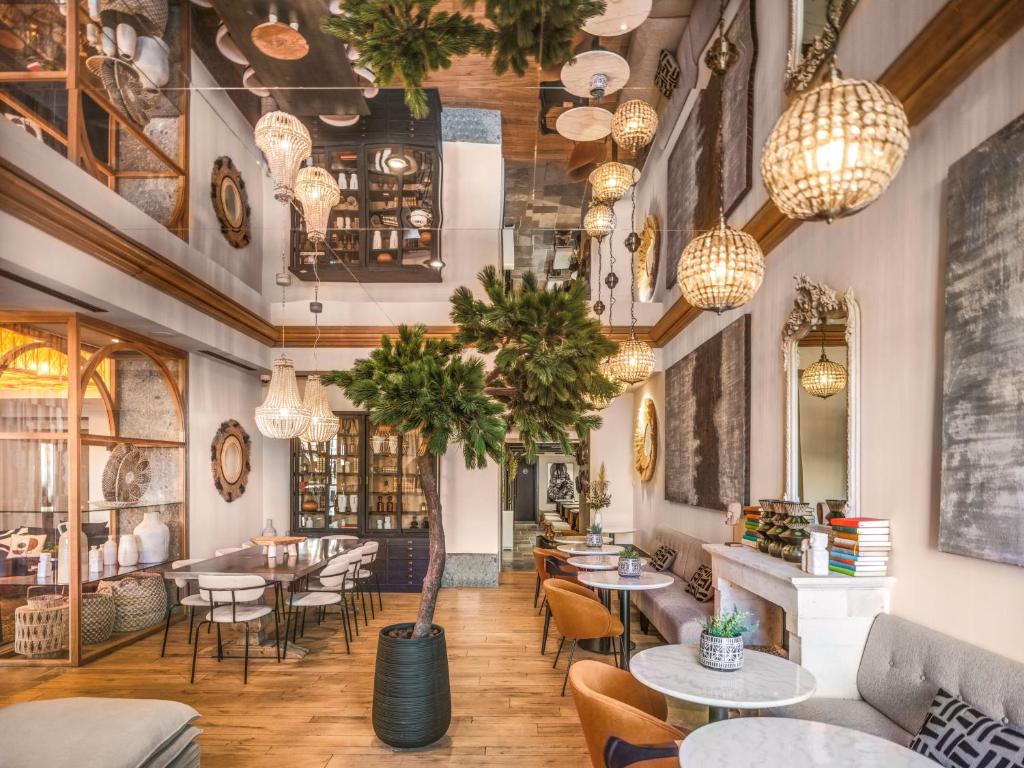 马赛Maisons du Monde Hôtel &amp; Suites - Marseille Vieux Port的有桌椅和吊灯的餐厅