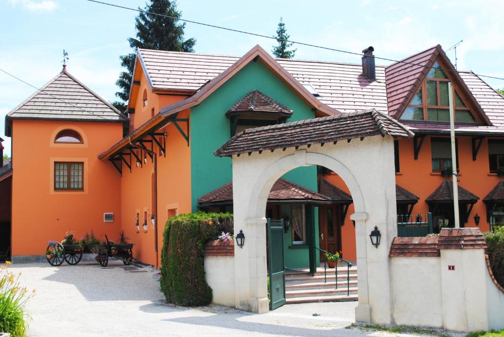 Le Vaudiouxl'Auberge des Gourmets Hôtel Restaurant的一座橙色绿色的房子,设有拱门