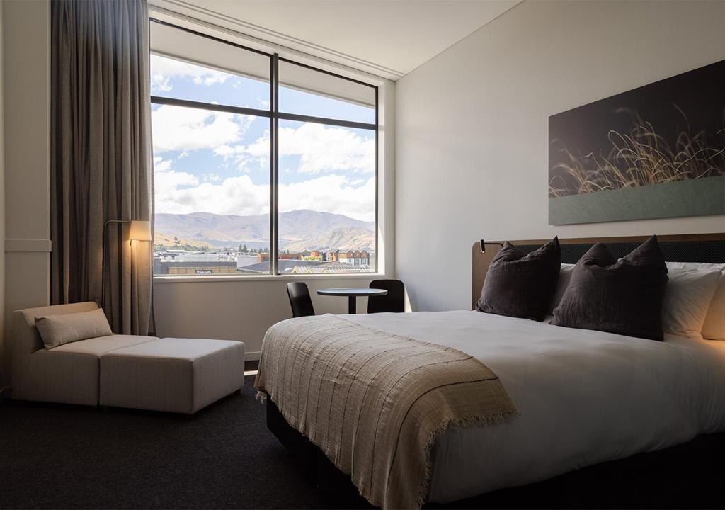 皇后镇Sudima Queenstown Five Mile的酒店客房设有一张床和一个大窗户