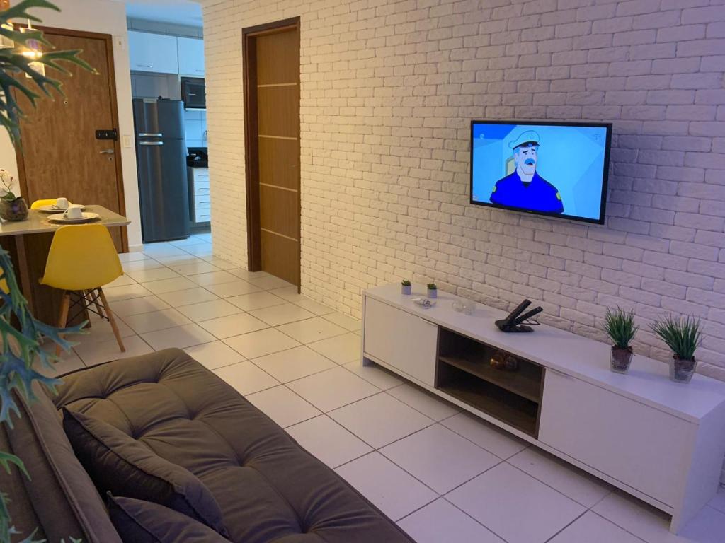马塞约Apartamento em Maceió的一间客厅,在砖墙上配有电视