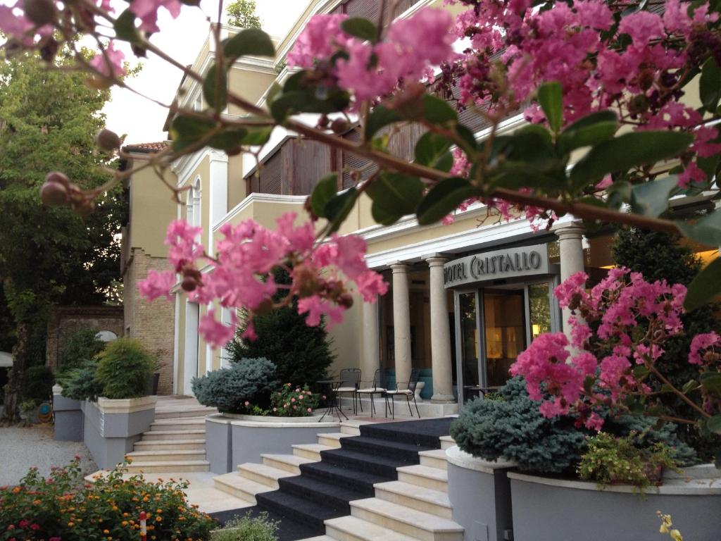 科内利亚诺克里斯塔罗酒店的前面有粉红色花的建筑