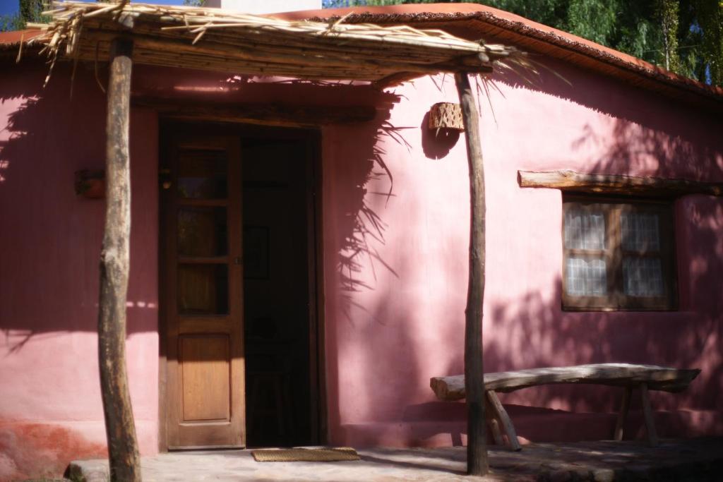 蒂尔卡拉La Calabaza Cabaña的粉红色的房子,外面有门和长凳