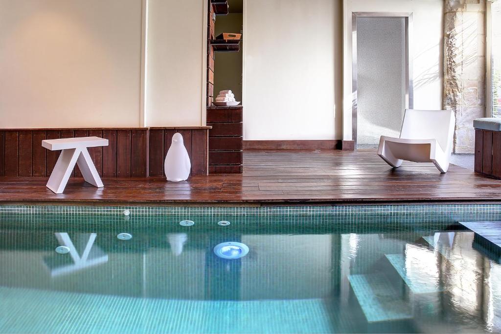 凯恩海豚和修道院Spa餐馆酒店的一个带两把白色椅子和一张桌子的游泳池