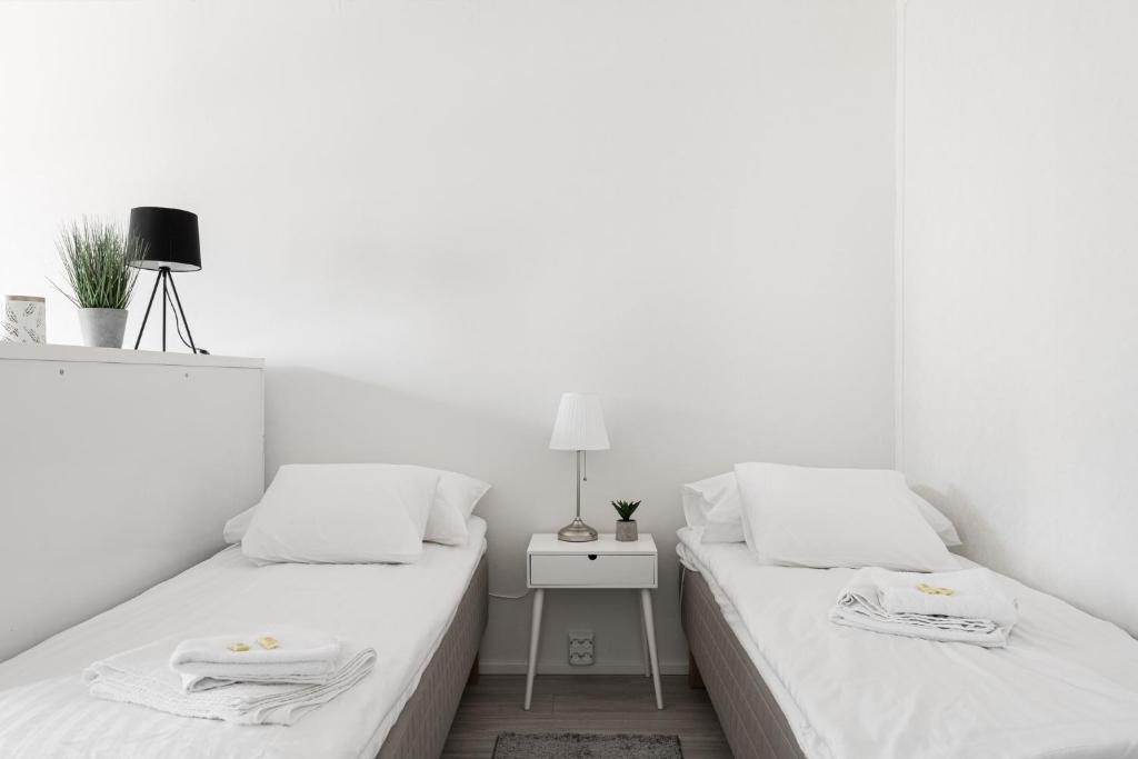 波里Apartments Borg Wellamo的白色客房的两张床,配有边桌