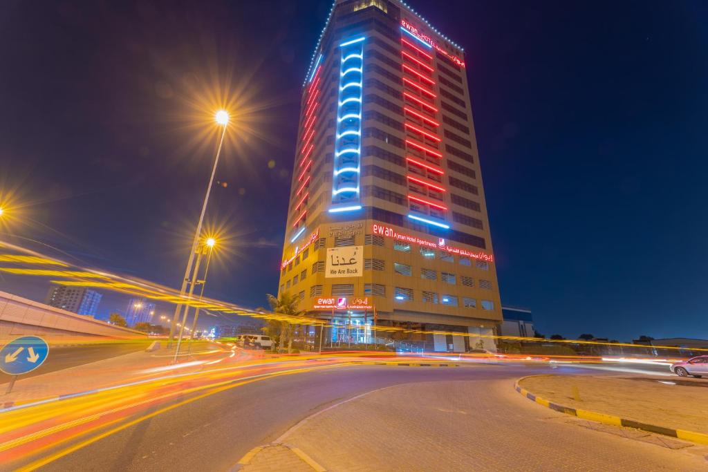 阿吉曼阿吉曼伊万套房酒店的一座高大的建筑,上面有红蓝的灯光