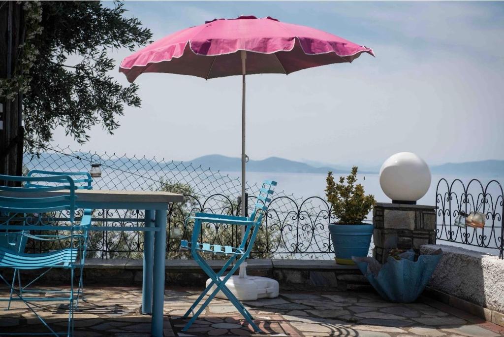 费索斯Panoramic sea & mountain view villa的粉红色的雨伞、两把椅子、一张桌子和一张桌子,