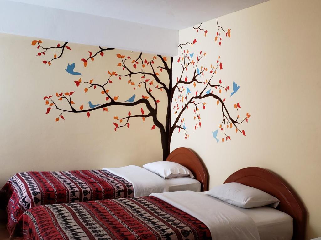 库斯科Nature Home Cusco的一间卧室设有两张床,墙上有一棵鸟树