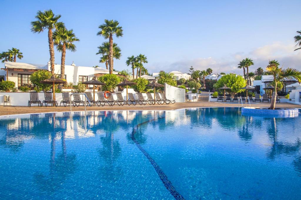 普拉亚布兰卡索尔花园钻石度假村的一座种植了棕榈树和建筑的大型蓝色游泳池