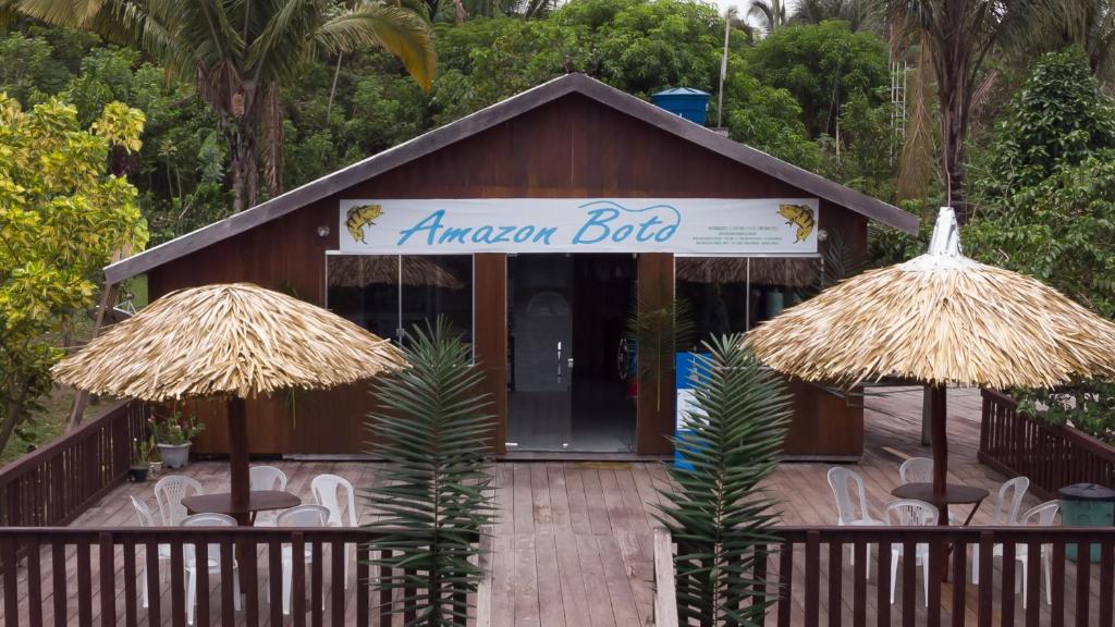 CareiroAmazon Boto Lodge Hotel的前面的餐厅设有椅子和遮阳伞