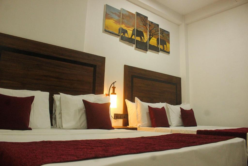 阿努拉德普勒Divine Villa的酒店客房带两张带红白色枕头的床