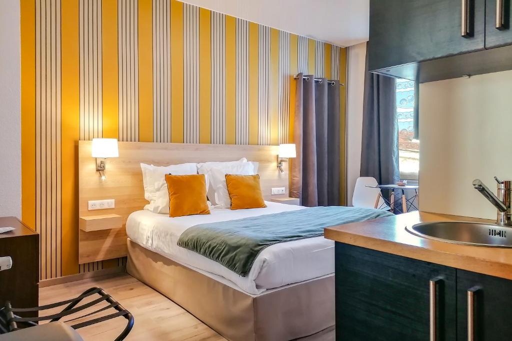 尼斯Aparthotel AMMI Nice Massena - ex Ajoupa的一间卧室配有带橙色枕头和水槽的床