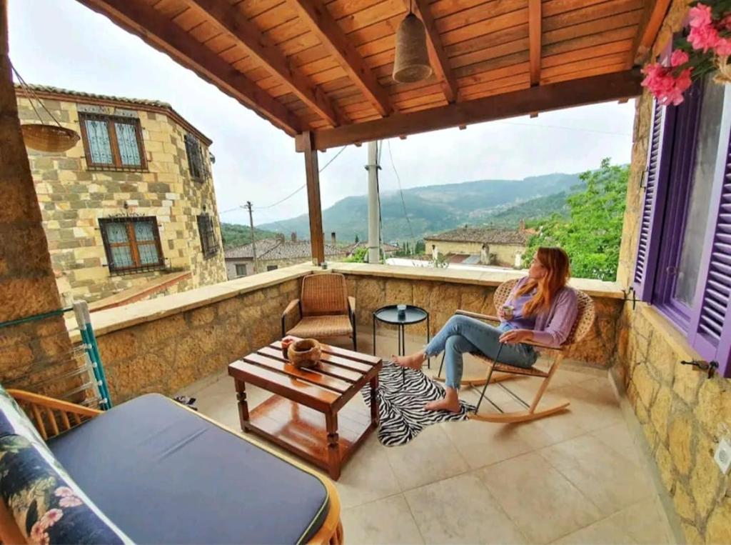 AyvacıkYerden Isıtma ve Şömineli Salvia - Sakin ve Bohem的坐在房子阳台上的女人