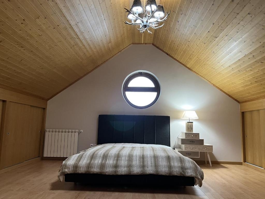 佩尼亚什达绍迪Estrela da Montanha的一间卧室设有一张大床和一个圆形窗户。