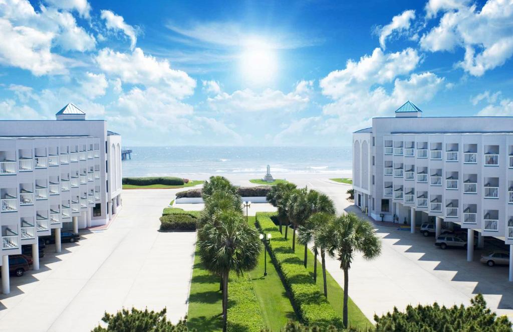 加尔维斯敦Casa Del Mar Beachfront Suites的享有两栋建筑和棕榈树以及大海的景致