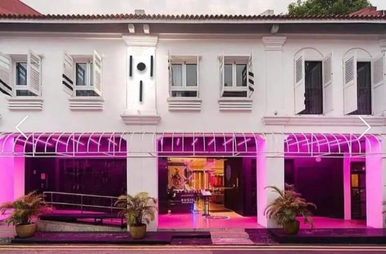 新加坡Hi Hotel的前面有粉红色灯光的白色建筑