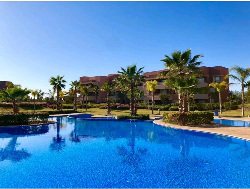 马拉喀什Marrakech golf city prestigia的一座大型游泳池,在一座建筑前种有棕榈树