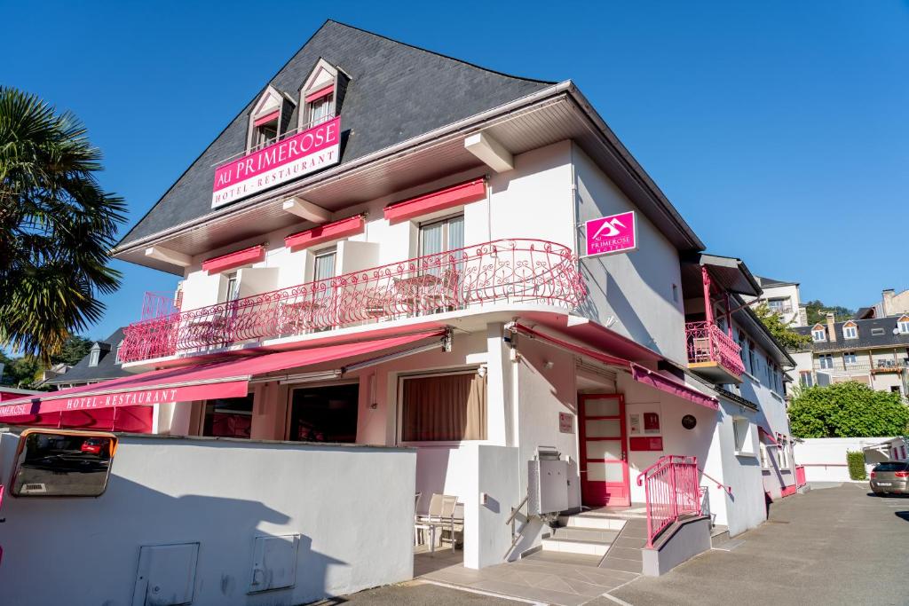 阿热莱斯加佐斯特Au Primerose Hôtel的带阳台的白色粉红色建筑
