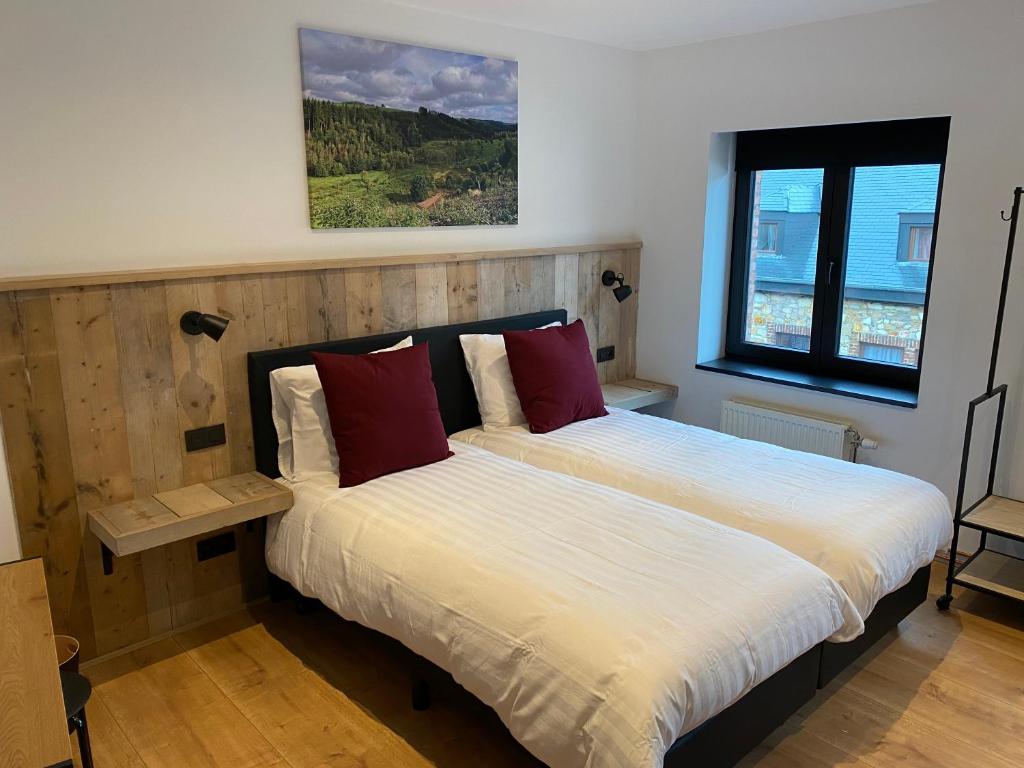 胡法利兹Rouleur Houffalize的一间卧室配有带白色床单和红色枕头的床。
