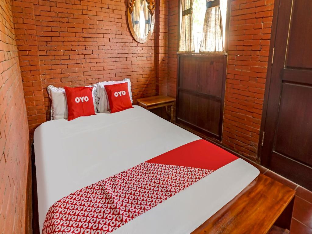 TrowulanOYO Homes 90948 Desa Wisata Kampung Majapahit的配有两张红色枕头的床的客房