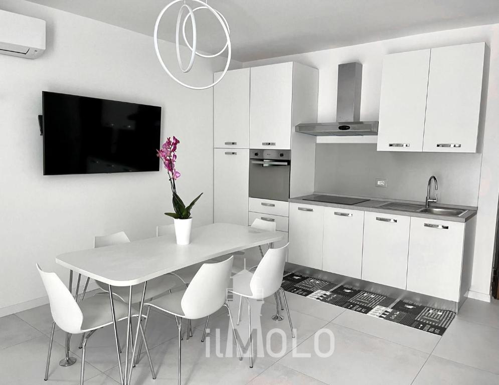那不勒斯Il Molo的厨房配有带白色椅子的桌子和电视。