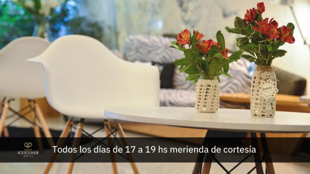 蒙得维的亚波西托斯广场酒店的桌子上放着两把白色椅子和两瓶花花瓶