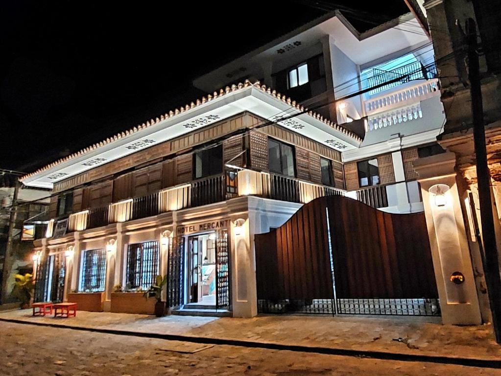 美岸Hotel Mercante的一座建筑,在晚上前有栅栏