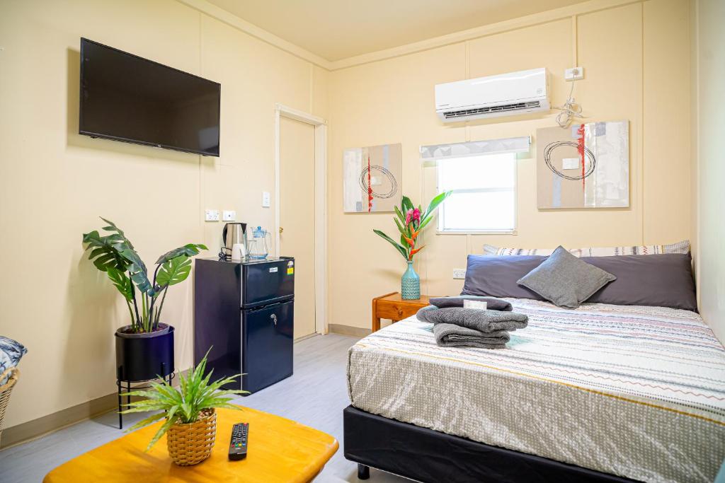 莫尔兹比港Green Hills Accommodation Village的卧室配有一张床铺,墙上配有电视