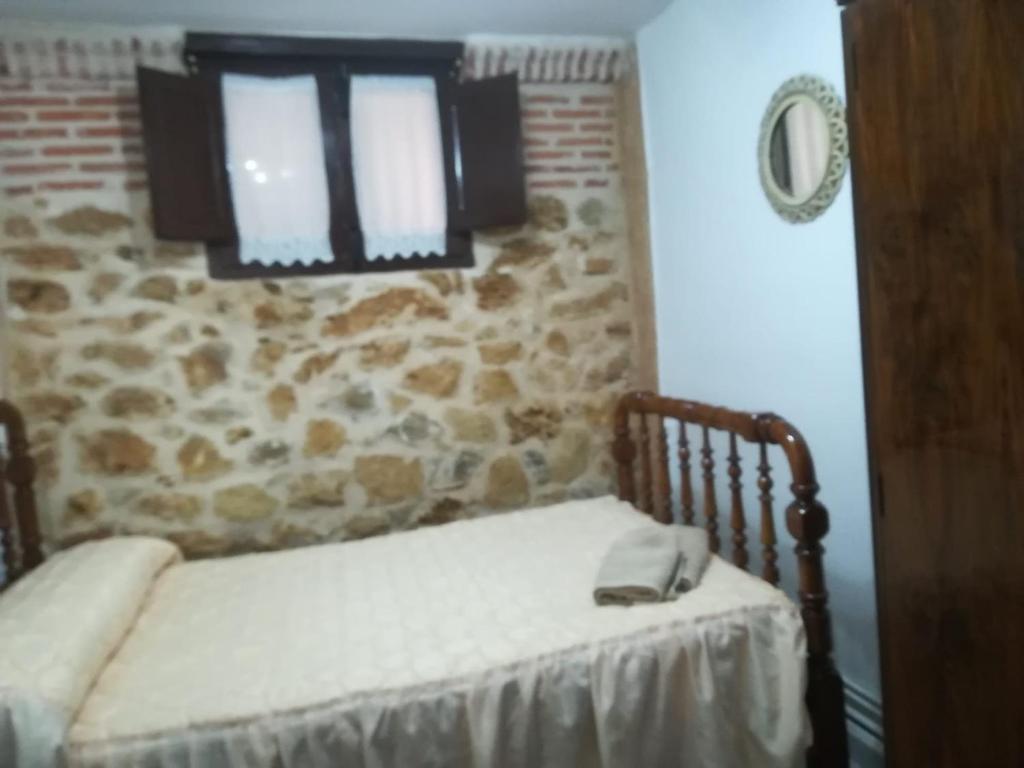 厄尔·布尔戈·德·奥斯马La casita del herrador的一间卧室设有一张床和石墙