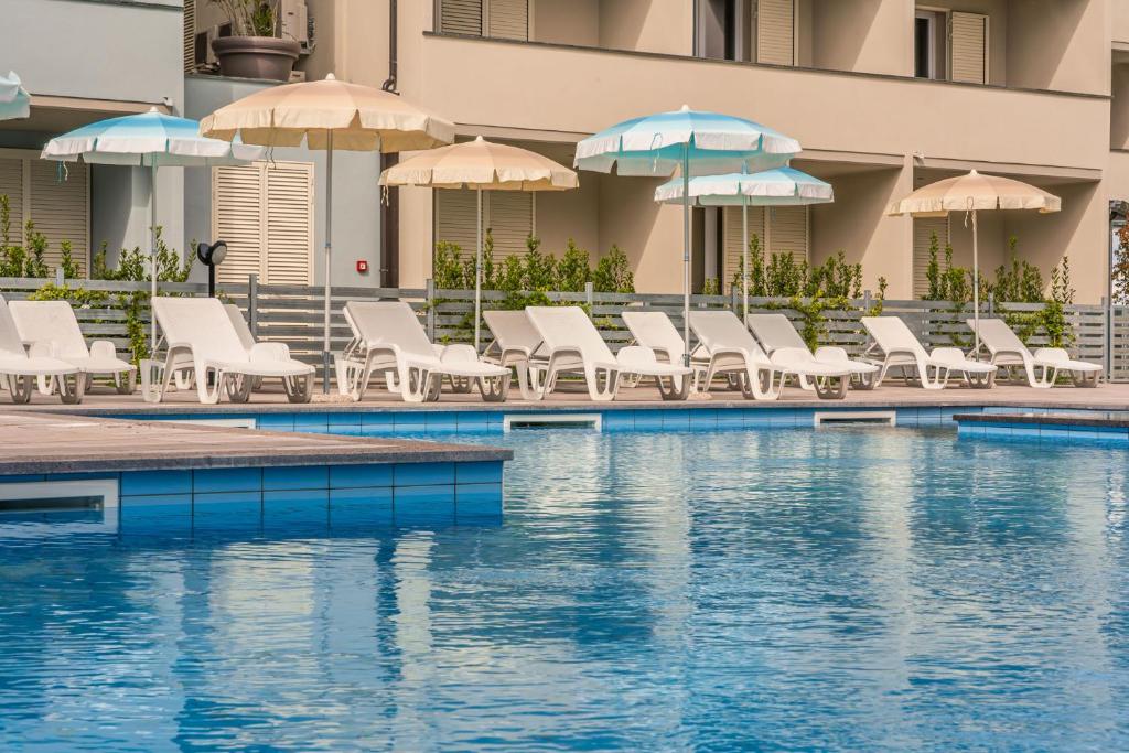 切齐纳码头Golden Hotel的一个带椅子和遮阳伞的游泳池和一个游泳池