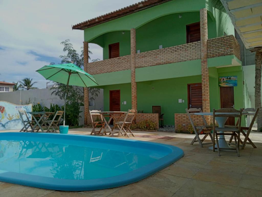 卡诺格布拉达Chalé do Aldo的一座带游泳池、椅子和遮阳伞的房子