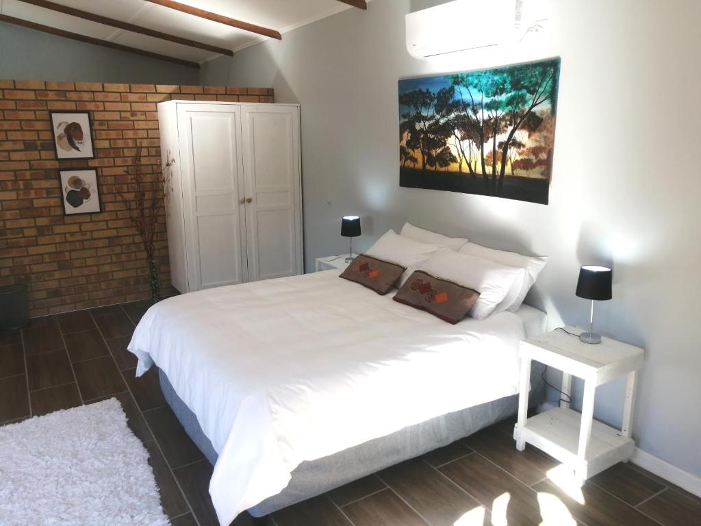 韦尔科姆Thatchers Guest Rooms的卧室配有白色的床和砖墙
