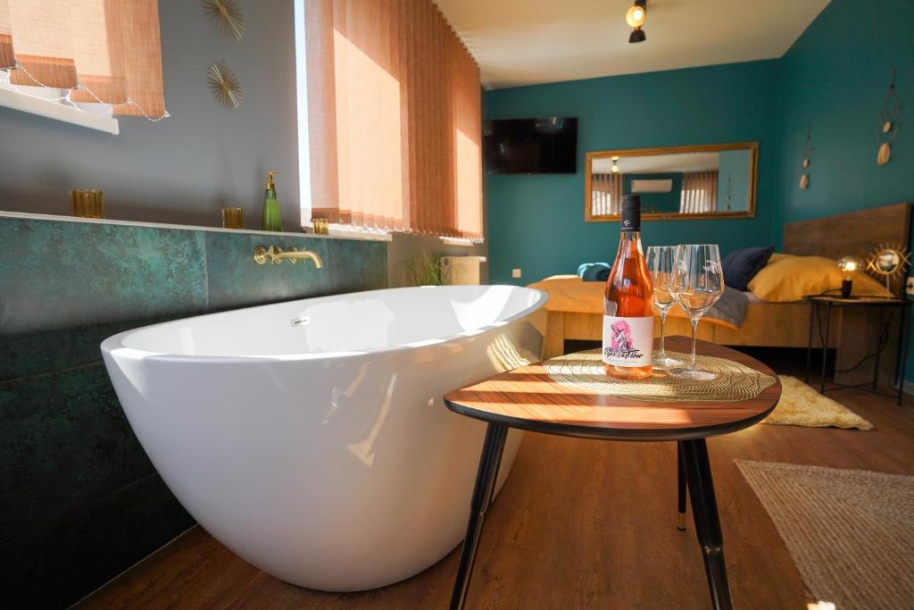 埃格尔Eger's Flow Apartment的带浴缸的浴室以及带一瓶葡萄酒的桌子。