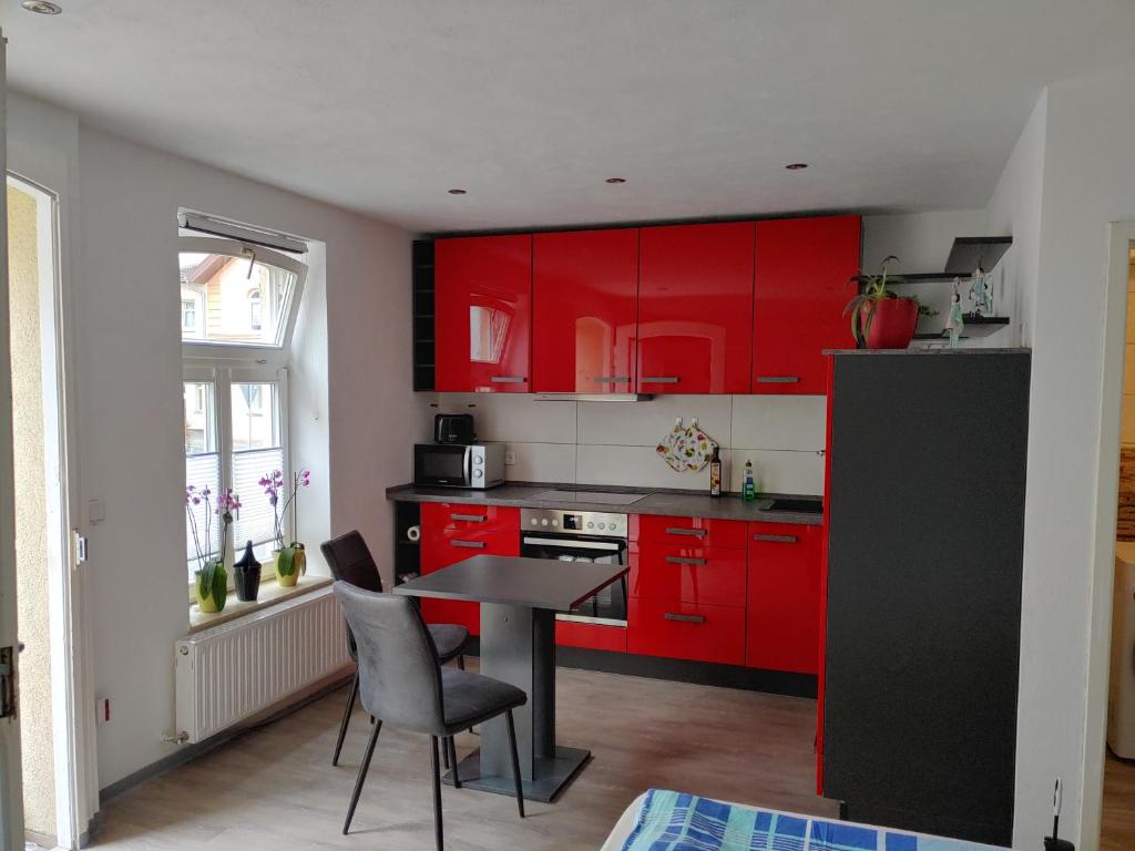 索内贝格Bei Charlotte的厨房配有红色橱柜和桌椅