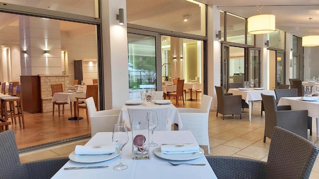 波利克罗诺Akrogiali Exclusive Hotel (Adults Only)的一间设有白色桌椅的用餐室