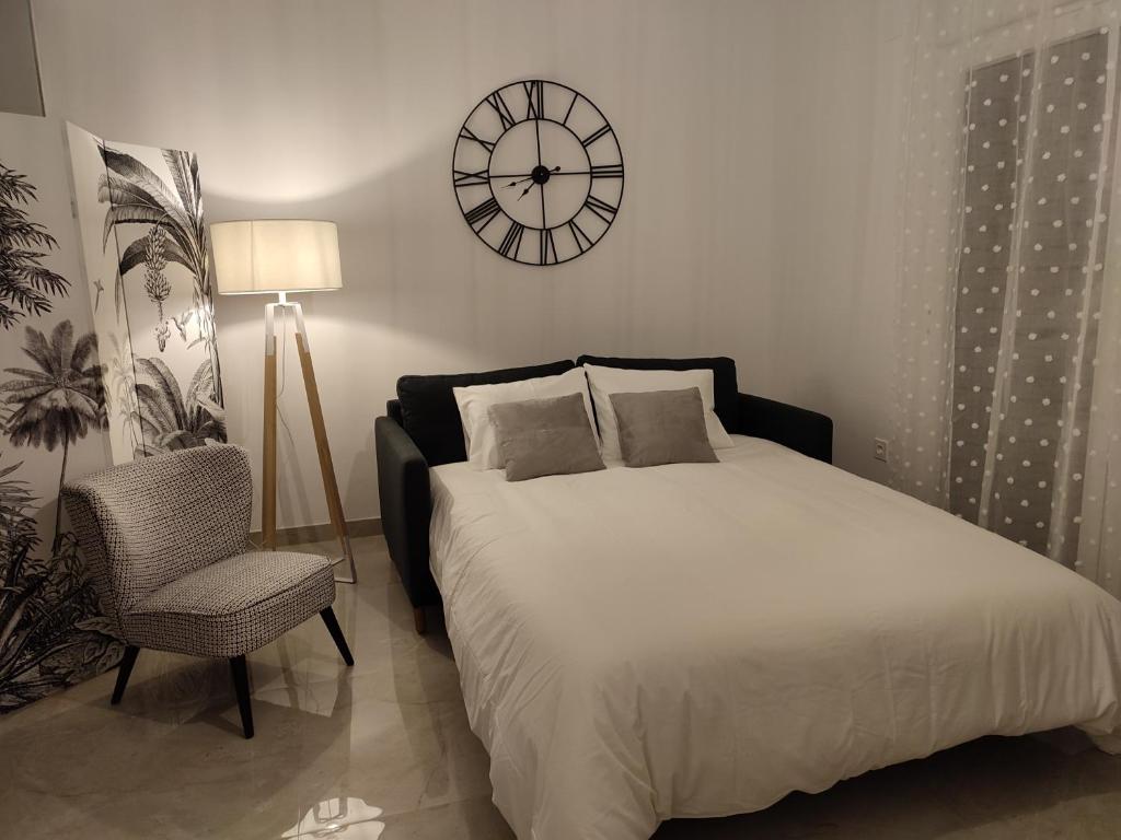 阿尔沃洛特APARTAMENTO ROMAR CHIC的卧室配有一张床,墙上挂着一个钟