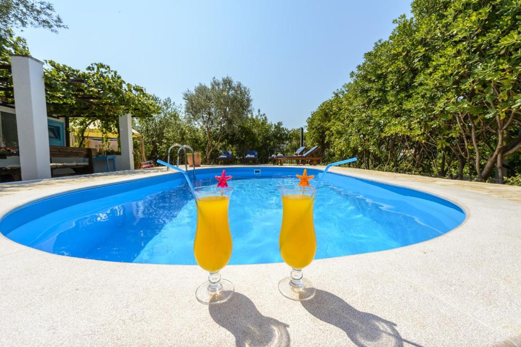 米利尼Villa Piano的两杯橙汁坐在游泳池旁