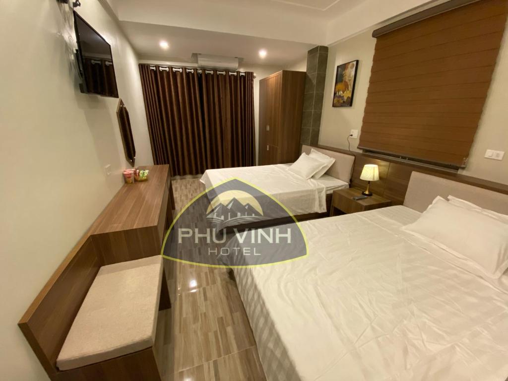 格卢市社Phú Vinh Hotel的酒店客房配有两张床和一张书桌