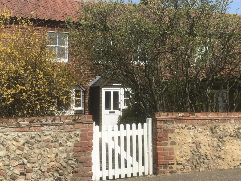 布兰克斯特Lovely 3-Bed Cottage in Brancaster Staithe的白色栅栏,在有白色门的房子前