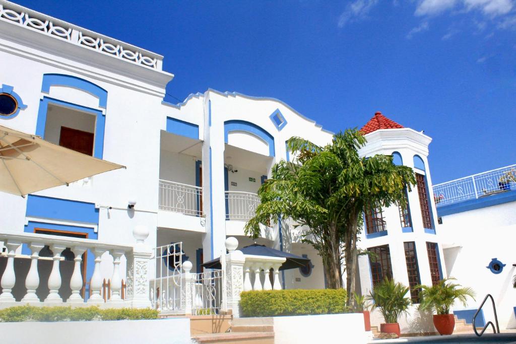 科罗萨尔Hotel Corozal Plaza的前面有棕榈树的白色房子