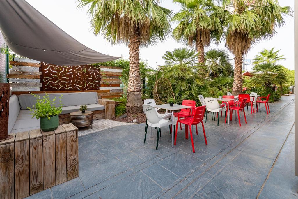 阿尔代阿瓦伦西亚博内尔宜必思酒店的庭院设有红色的桌椅和棕榈树