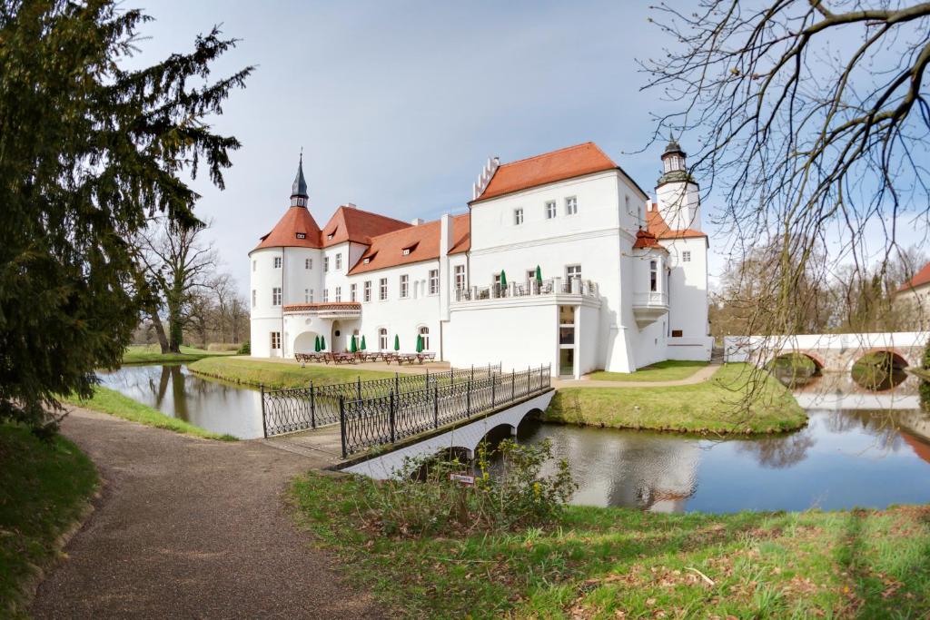 Drehna弗斯蒂申德瑞赫城堡酒店的一座巨大的白色城堡,桥上横跨河流