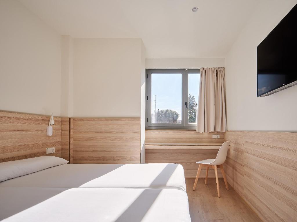 埃斯普卢加·德·隆布雷格拉米酒店的一间卧室配有一张床、一台电视和一把椅子