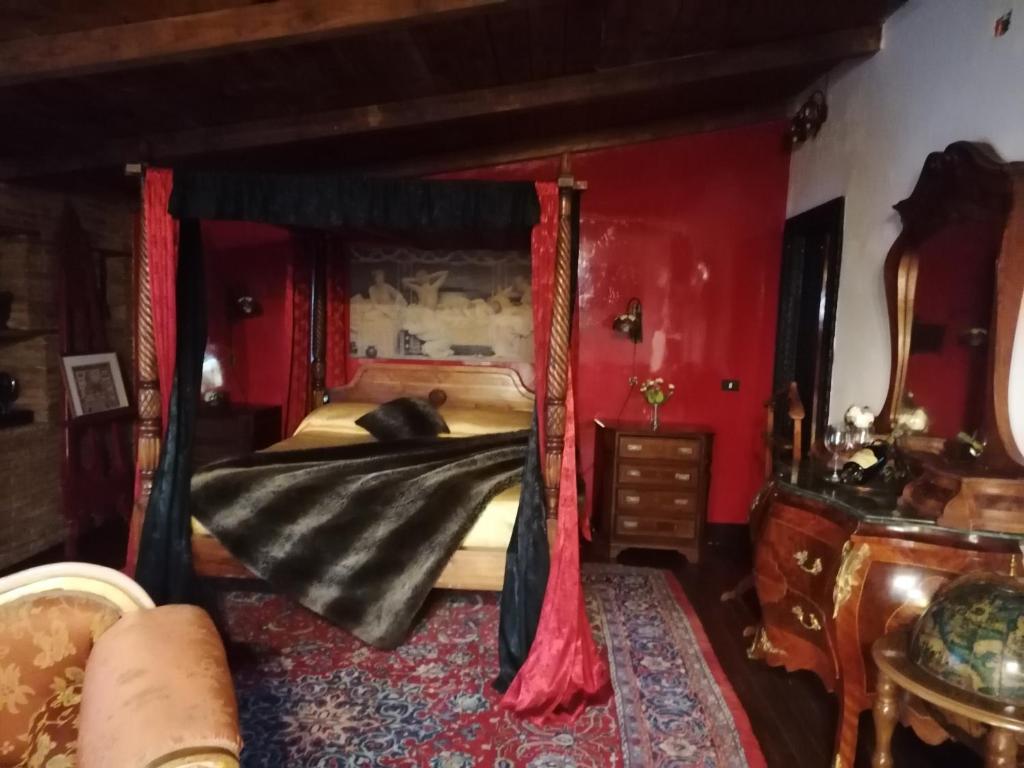 安圭拉萨巴齐亚La stanza nel parco的一间卧室配有一张带红色墙壁的天蓬床
