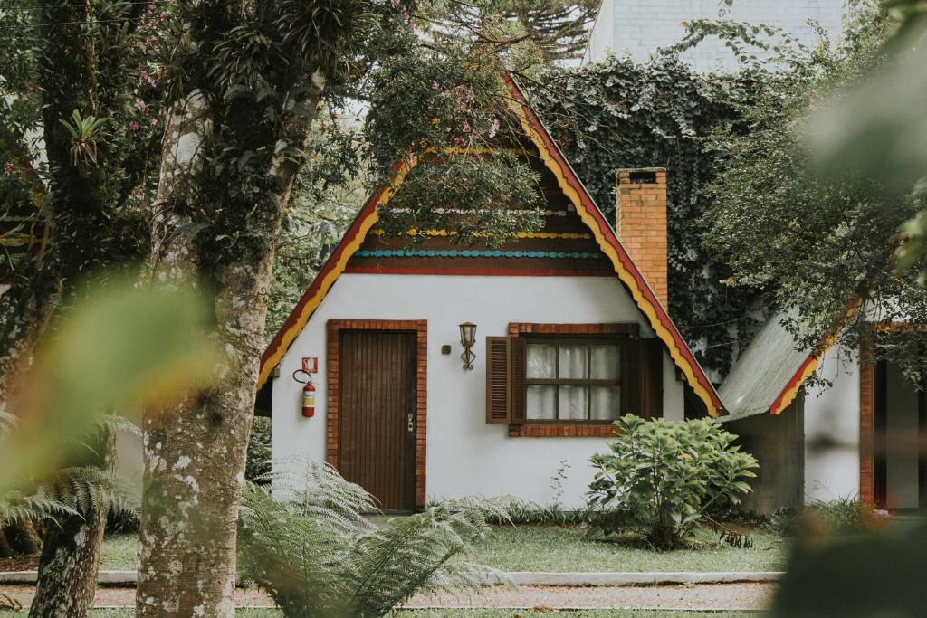 格拉玛多Villa De Chalés Gramado- OH HOTÉIS的白色的小房子,有屋顶