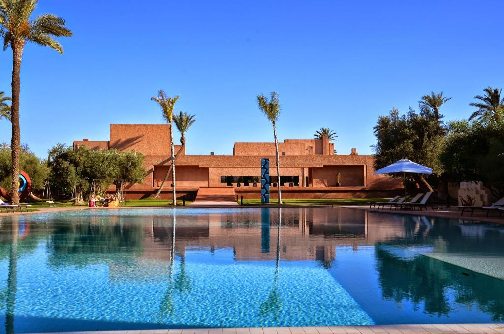 马拉喀什达尔萨布拉酒店的棕榈树建筑前的游泳池