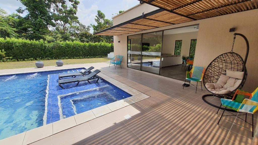 比亚维森西奥Finca los Colores的一个带游泳池、椅子和房子的庭院